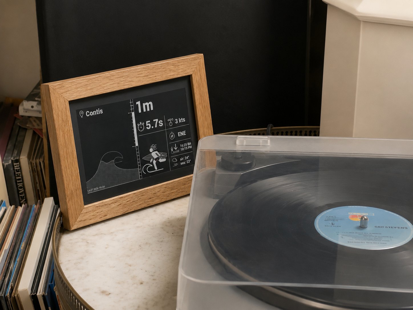 Cadre de chêne affichant la houle, posé près d’une platine vinyle.